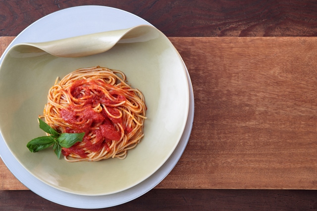 丸皿に盛りつけられたチェリートマトのソースを使ったトマトパスタの写真