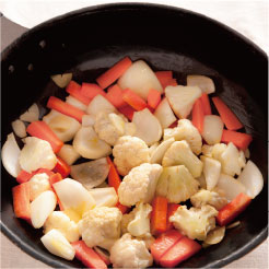オリーブオイルで揚げた野菜にホワイトバルサミコ酢をかけている調理写真